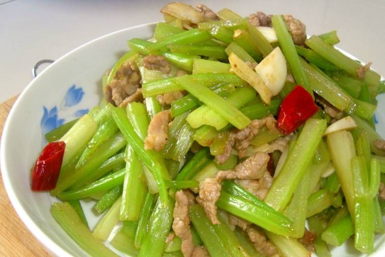 4,热锅凉油,下入肉丝炒散,肉丝变色后,放入辣椒,蒜片,芹菜段.