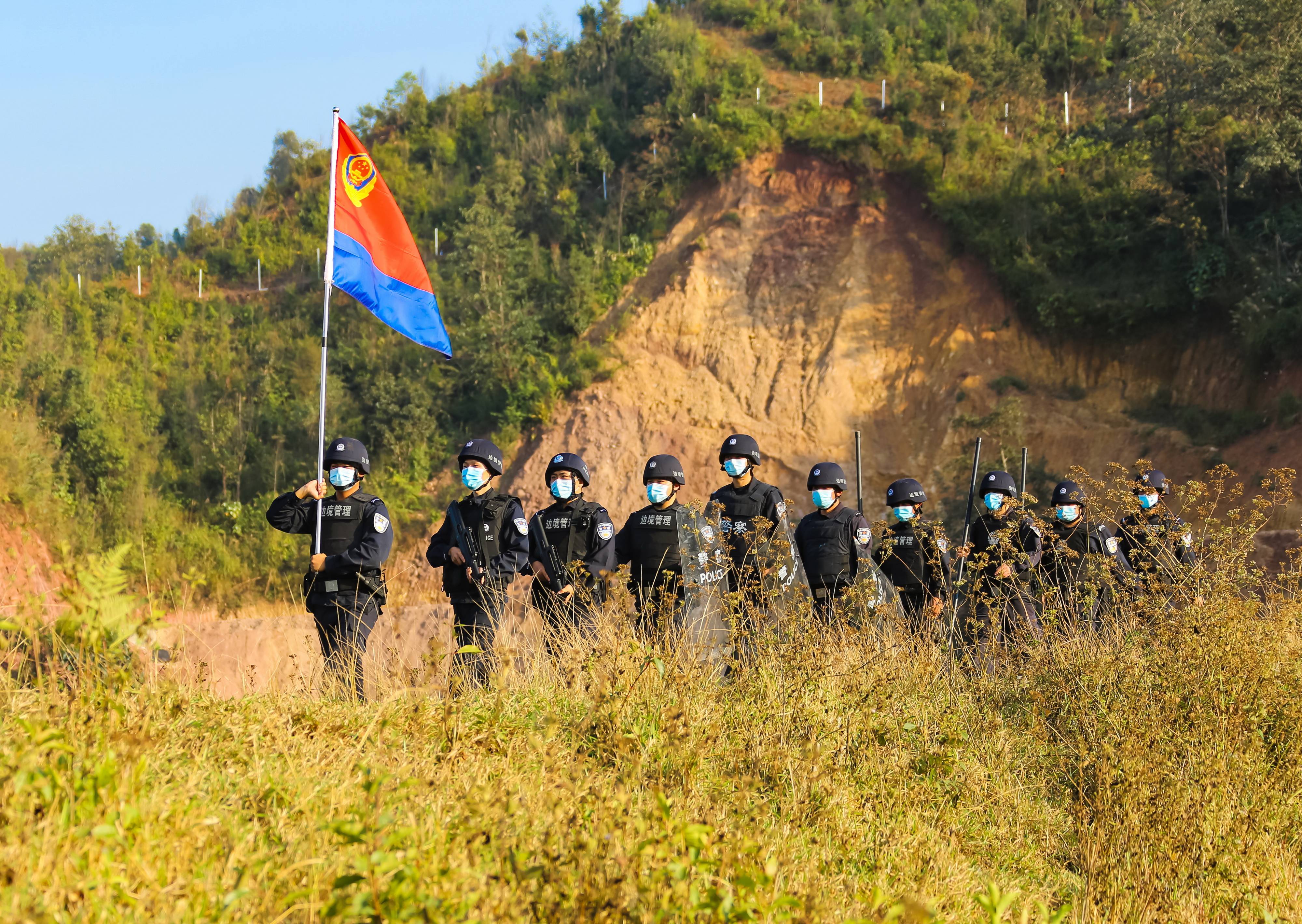 云南普洱边境管理支队民辅警手持中国人民警察警旗开展边境巡逻