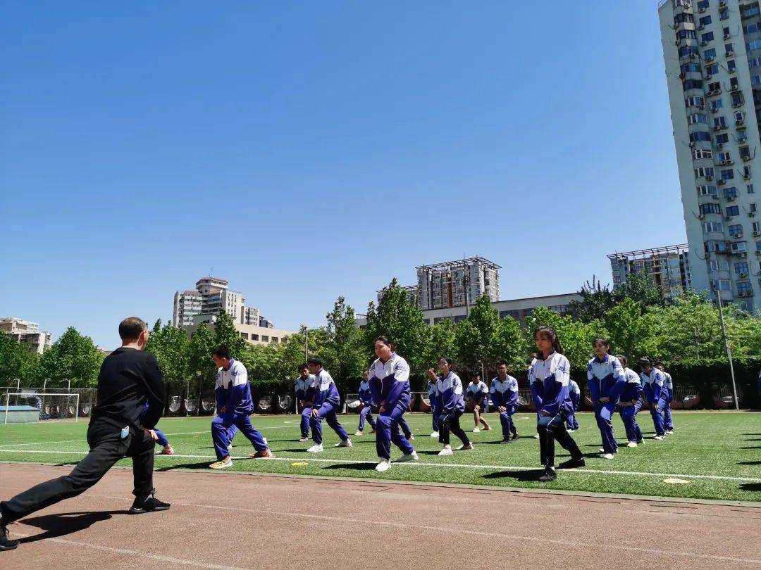 赵登禹学校体育老师带着初三的同学们做拉伸热身运动