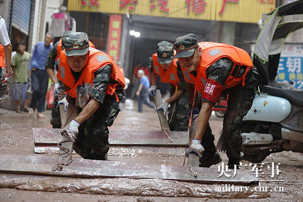 7月18日,在重庆市万州区五桥镇,武警官兵正在清理路面淤泥.邹毅摄