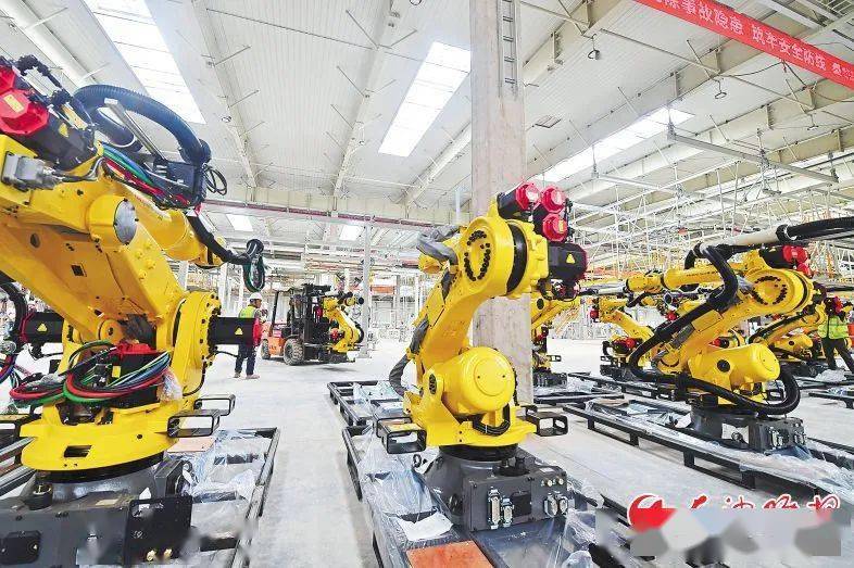 在焊装车间,工作人员将机械臂安装在生产线上.