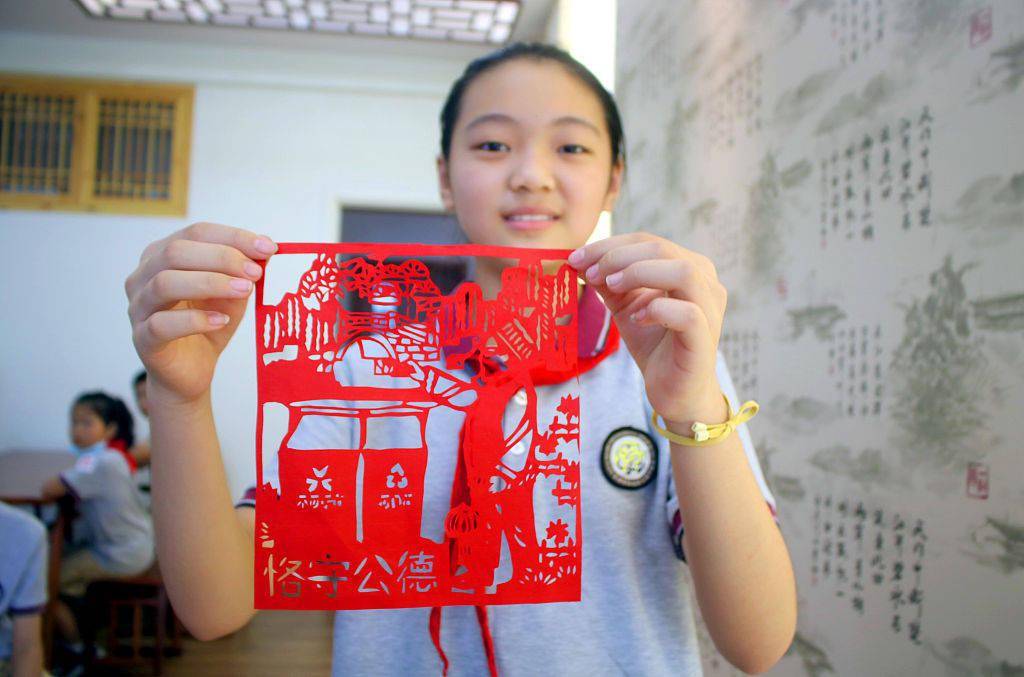 江苏省苏州市阳光城实验小学校的一名学生展示垃圾分类内容的剪纸作品