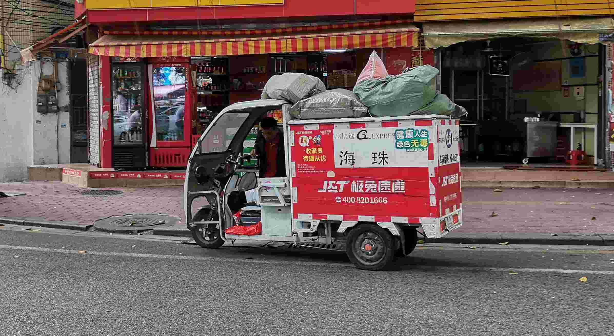 不停搬运堆积在门口的快递包裹,一辆辆派送三轮车进出驿站,等待包裹装