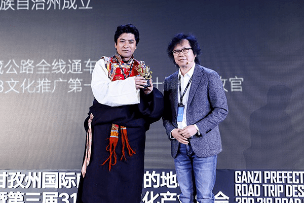 甘孜州文化广播电视和旅游局局长刘洪(左)与"国民公路g318"文化推广