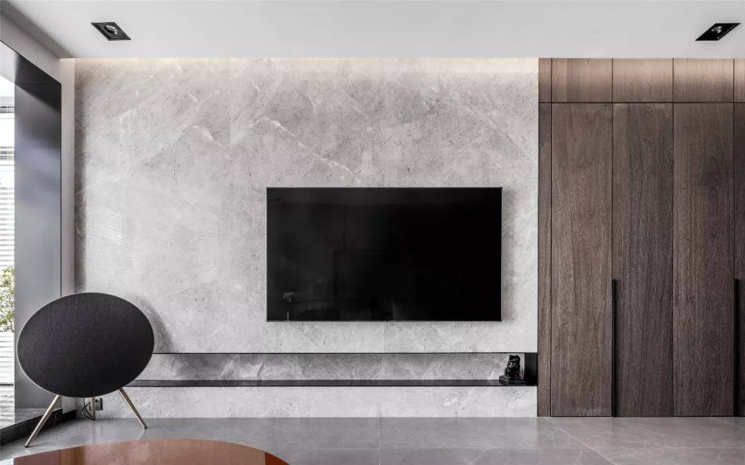 极简风格的电视背景墙与木纹,石材形成了独有的成熟内敛气质.