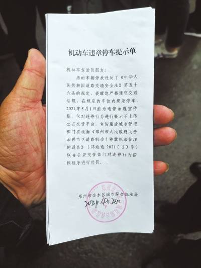 城管部门工作人员对路边违停车辆粘贴《机动车违章停车提示单□顶端