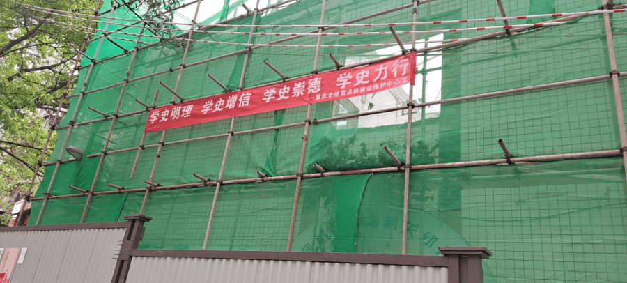 市设施中心在办公区域和体操房改造工程工地悬挂横幅标语,让党史学习
