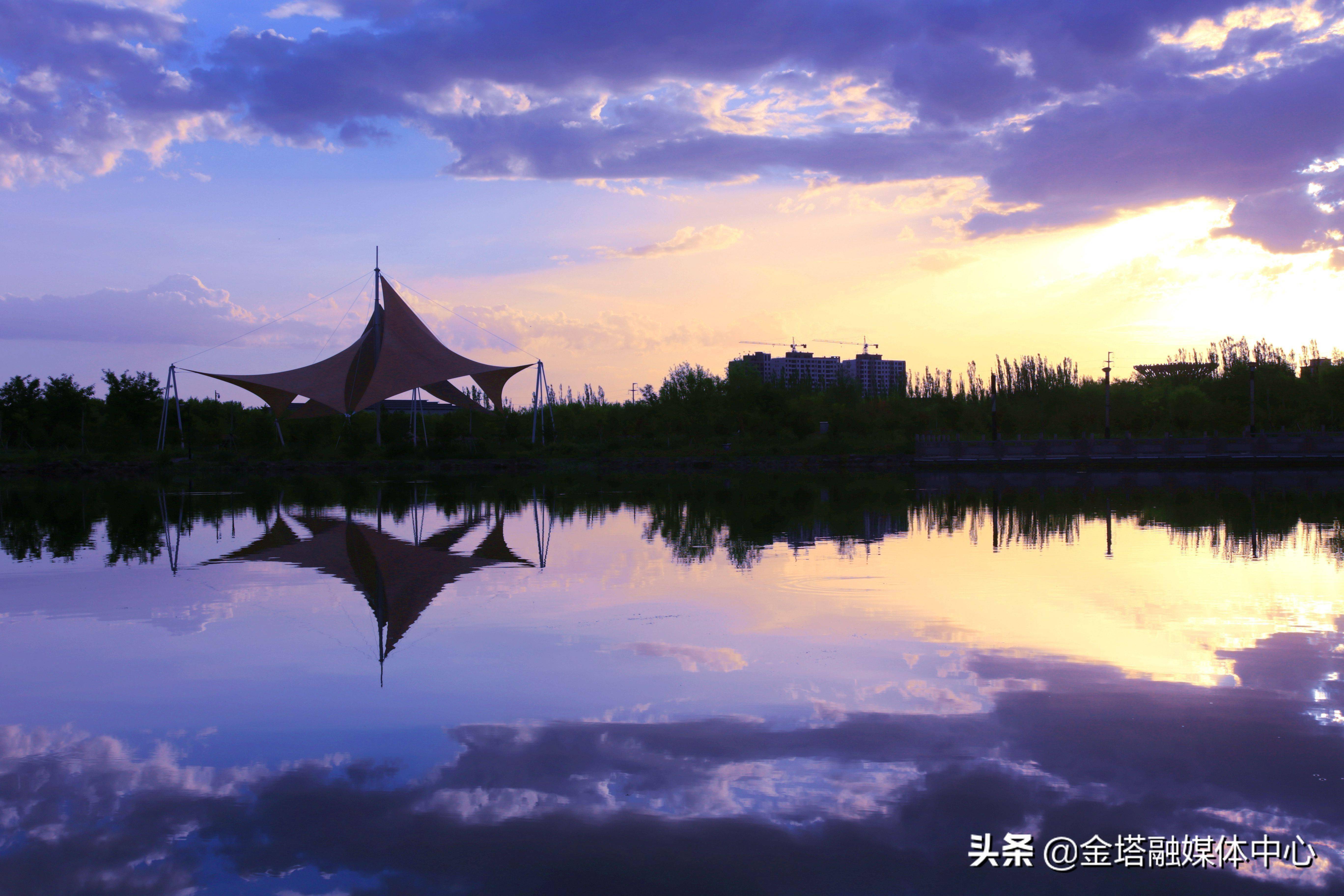 夏日的傍晚,酒泉市金塔县湖面被笼罩在落日余晖下,仿佛铺开一幅美丽