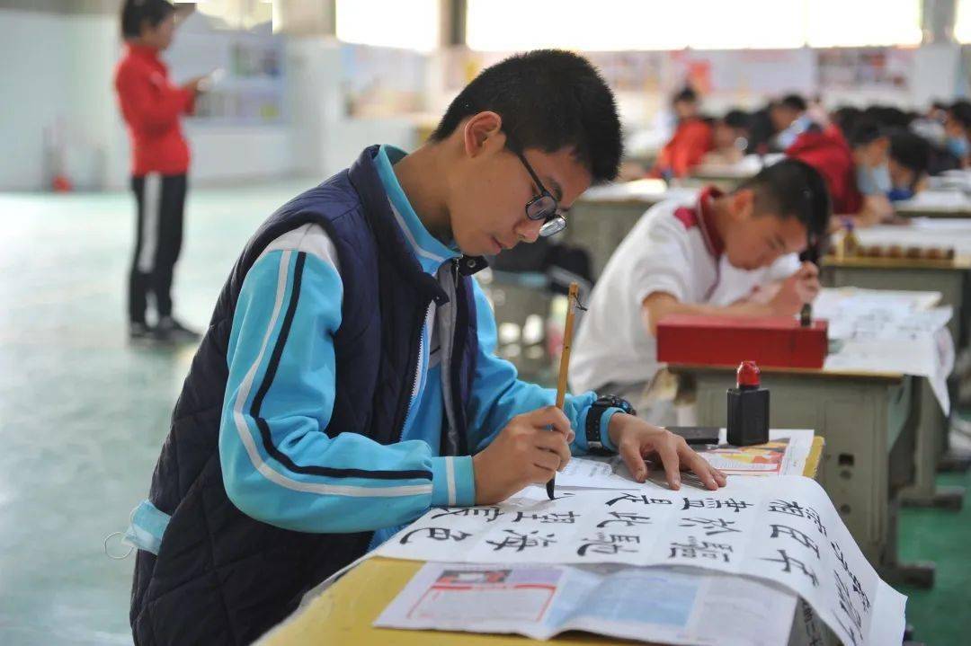 书法比赛现场，墨香四溢，硬笔、毛笔参赛选手沉稳自若，举手投足间颇具