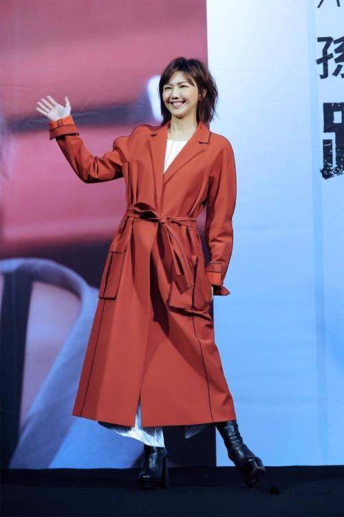 下图照片中,孙燕姿穿了一件白色衬衫搭配红褐色宽松风衣外套,看着像个