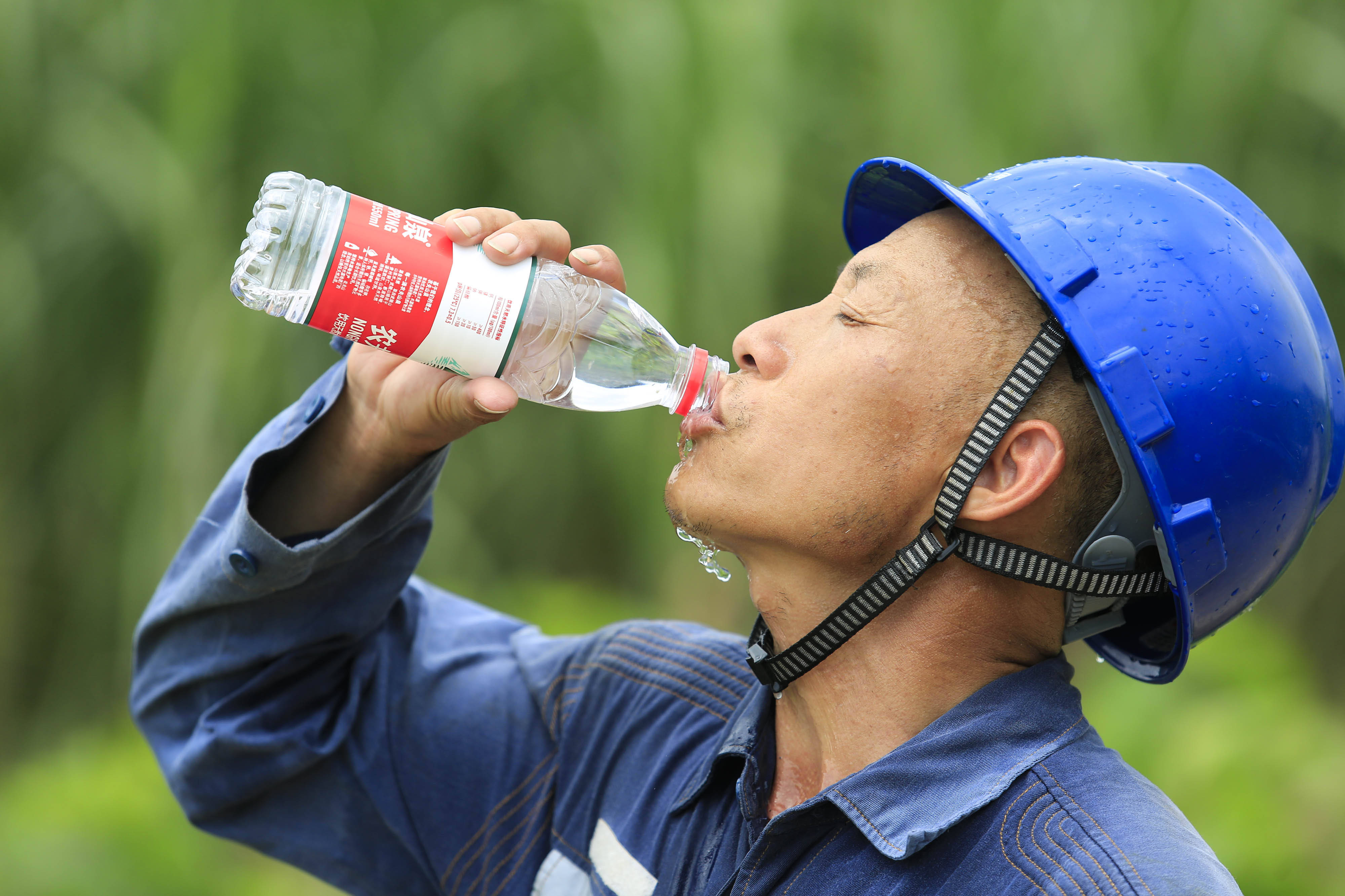 在柳城县大埔镇三塘村,一名电力工人在喝水解渴