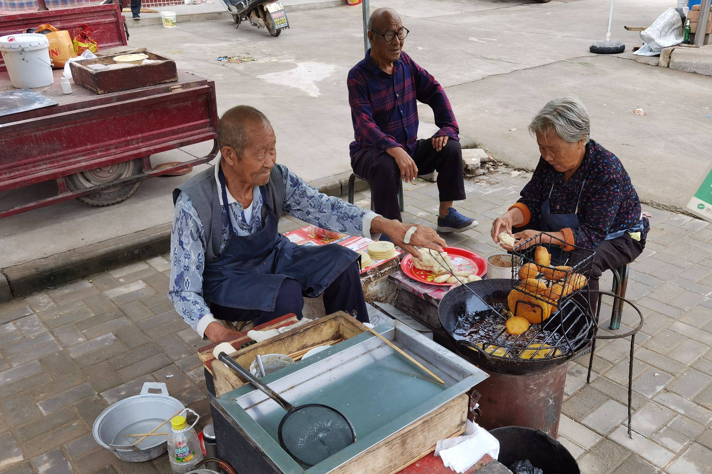 恩顺和老伴在卖着自家的美食摄影师一边品着美食一边和老人家拉呱起来