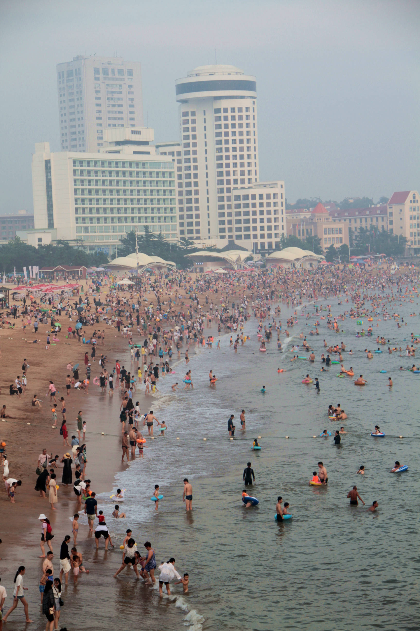 秋老虎发威,青岛海水浴场密密麻麻人群如下饺子