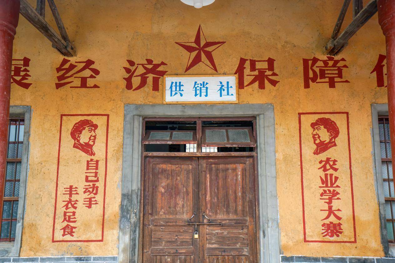 来到围屋的附近,发现了一处供销社,木门,20世纪60年代的标语,还有毛