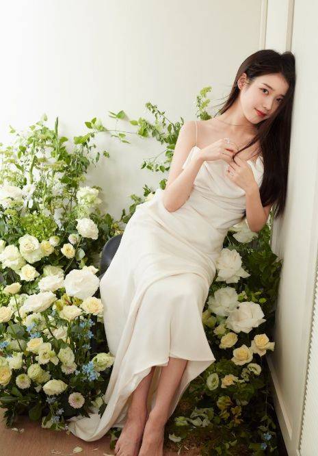 iu身穿白色抹胸长裙,发型弄成微卷长发披在肩上.