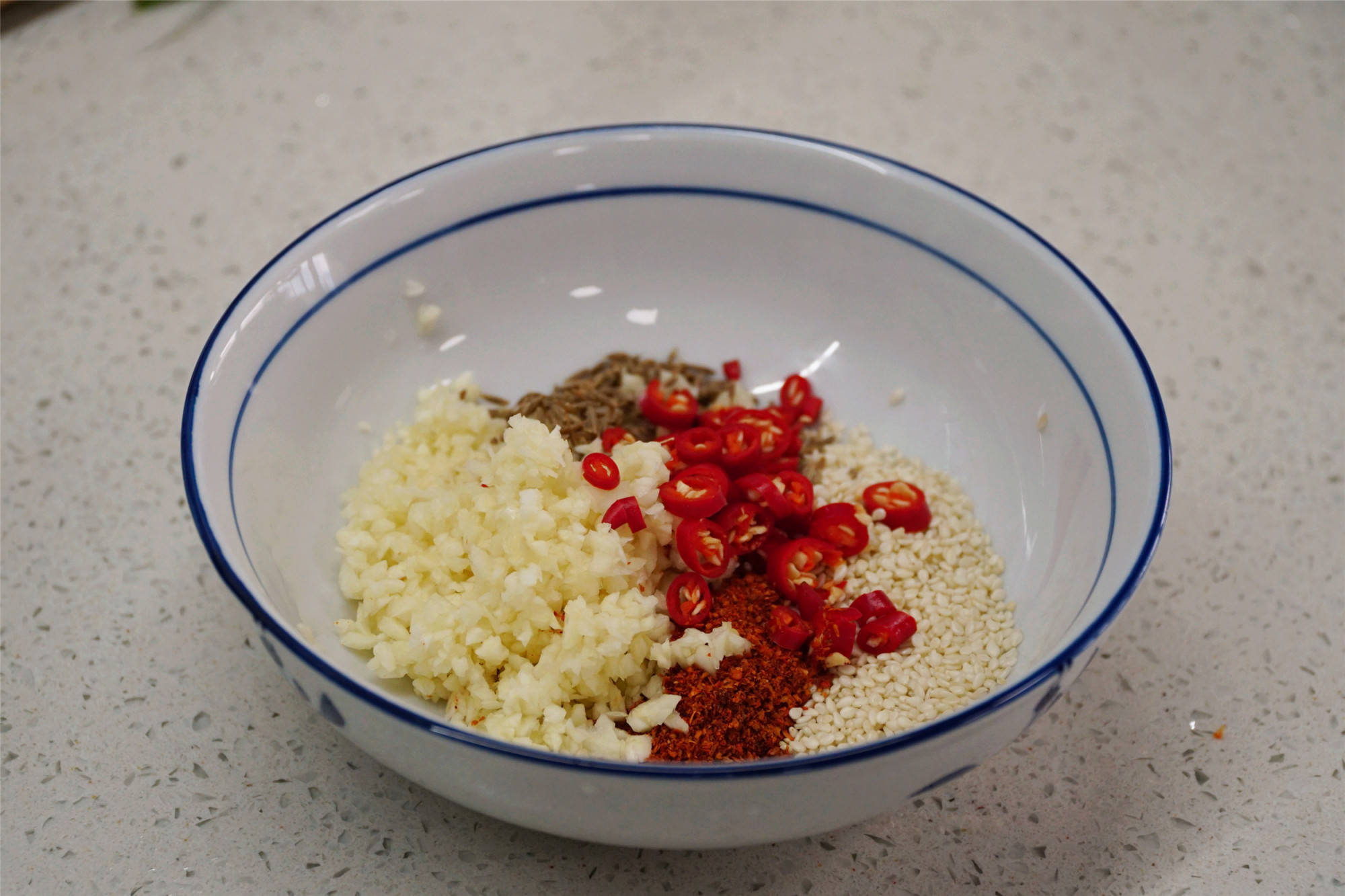 调一个好吃的料汁,碗中加入2勺蒜末,1勺白芝麻,1勺孜然粒,1勺辣椒粉