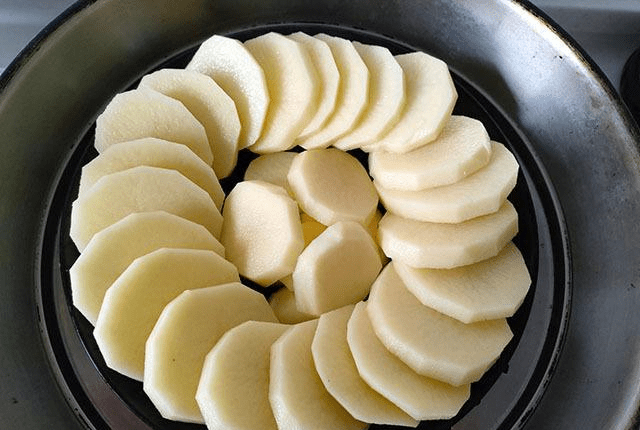 4,蒸好的土豆取出,然后沿着边缘淋入料汁,中间放上葱丝和辣椒丝摆盘就