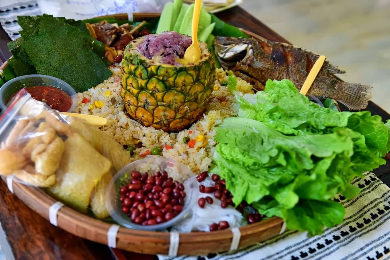 大筲箕上铺上一层芭蕉叶,将傣族美食集合荤素搭配,加上食材染出的彩色