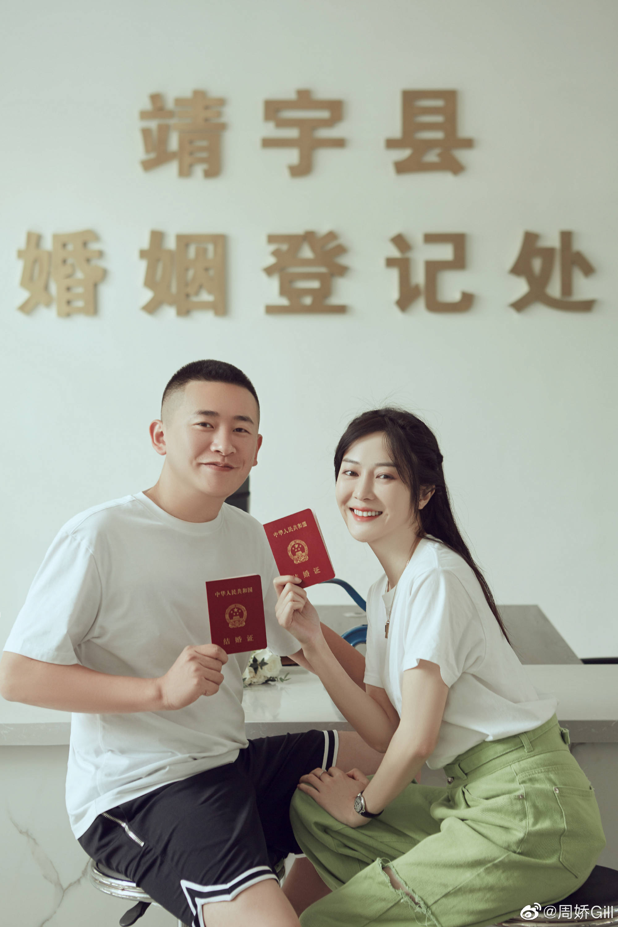 在民政局大厅内各自手持红本本(结婚证)齐齐对着镜头面露灿笑拍照留念