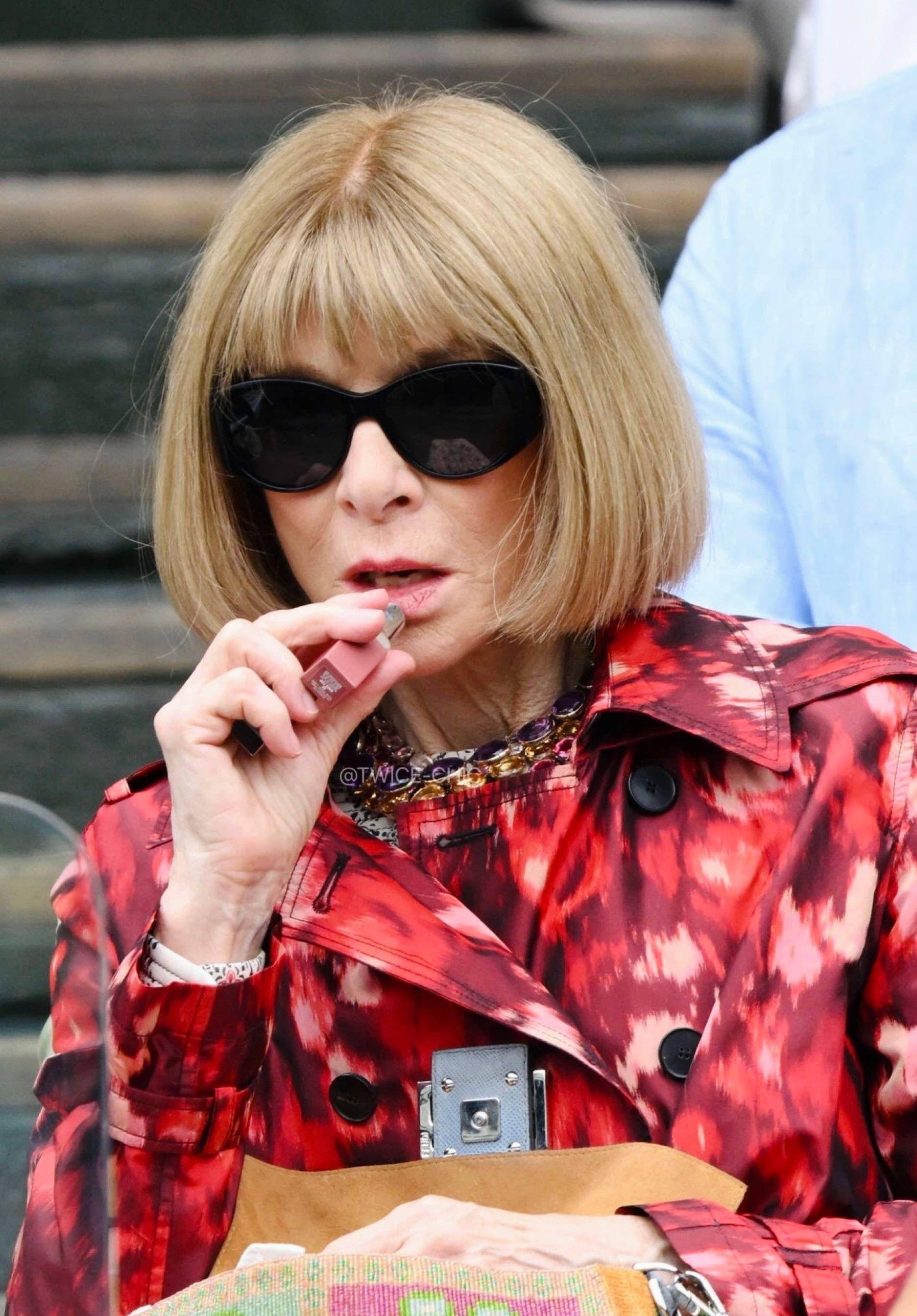 那天,她穿着红色印花风衣,坐在看台上自然地涂着口红,金色的波波头与