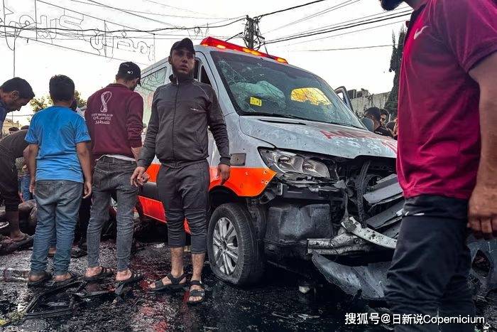 人们聚集在一辆在希法医院门前的爆炸中受损的救护车周围.