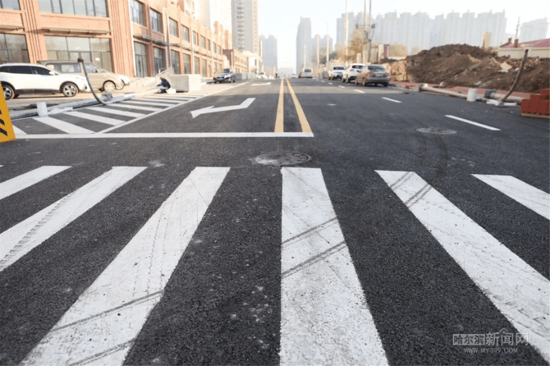 车行道路面已基本铺设完毕,施工人员正在进行人行道的铺装