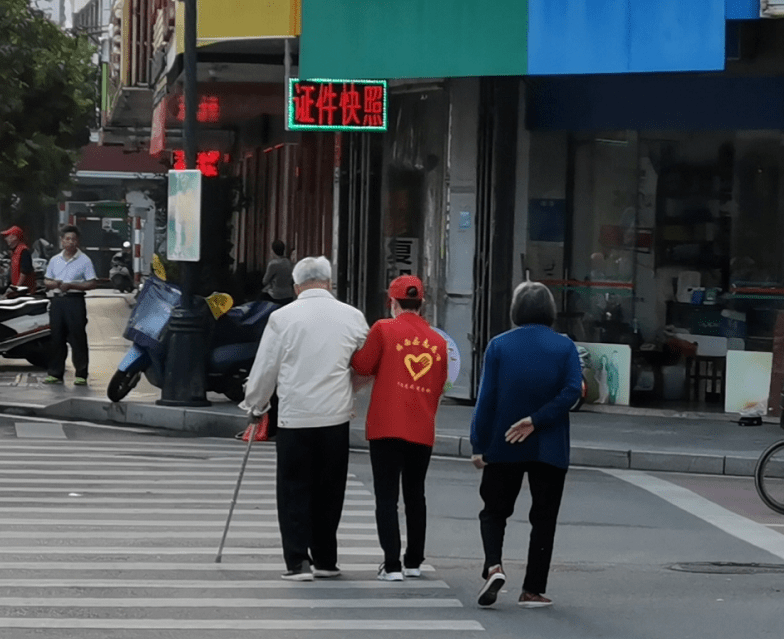 志愿者扶老人过马路交警扶老人过马路干部群众齐参与 保持大街小巷