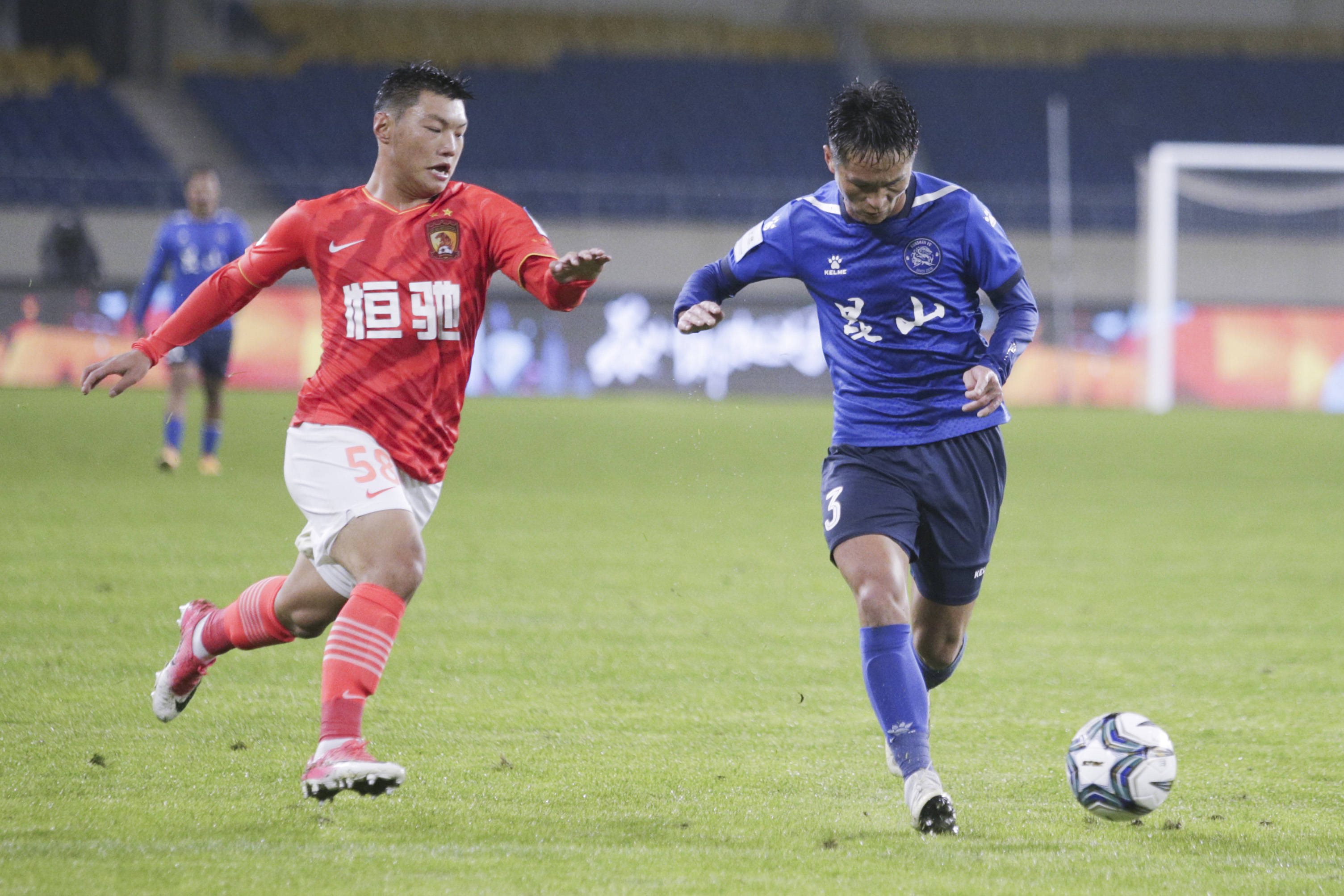 11月26日,广州恒大淘宝队球员吴俊杰(左)与昆山fc队球员曹海清拼抢.