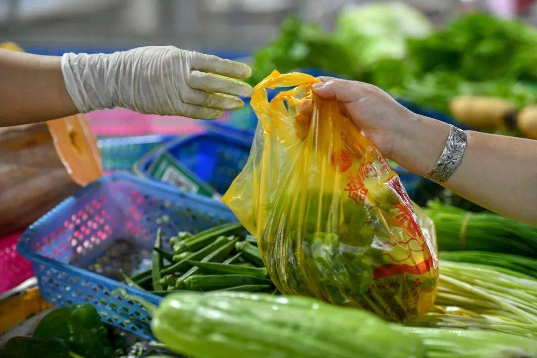 民众在农贸市场买菜用塑料袋包装.骆云飞摄