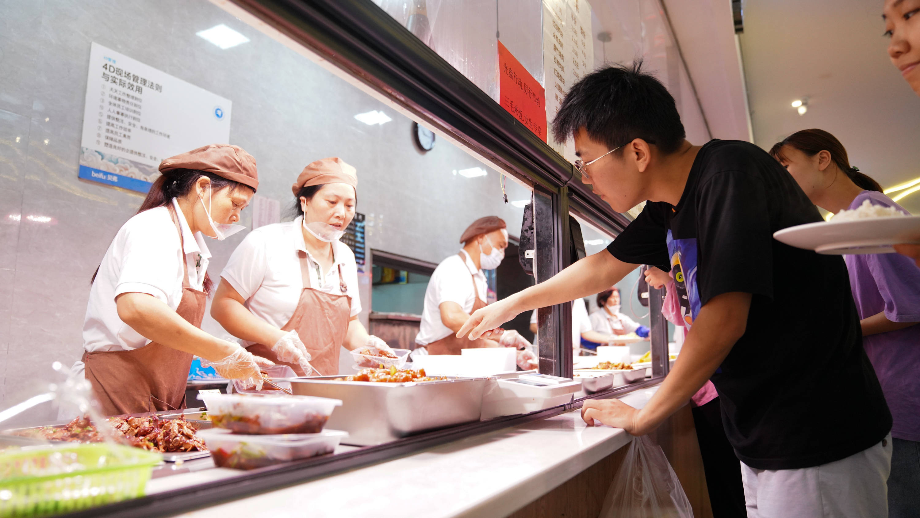 6月1日,赵建军在学校食堂内为母亲打饭