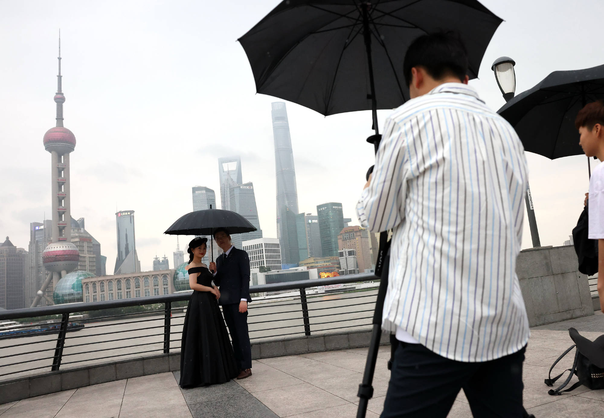 6月10日,游客在雨中的上海外滩拍摄艺术照片