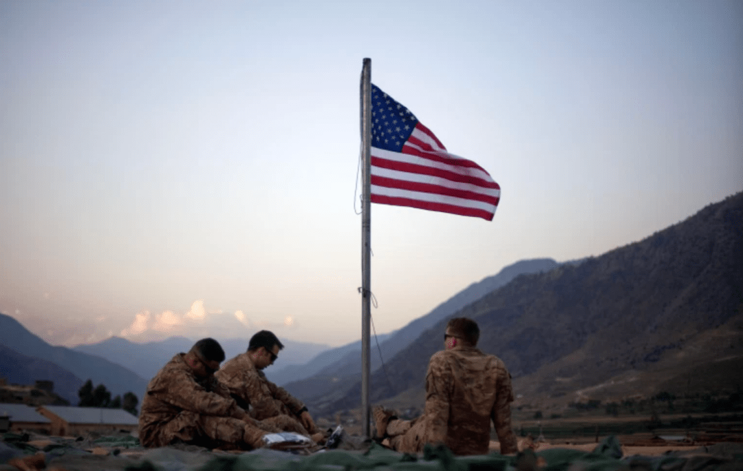 驻阿富汗的美国士兵坐在一面刚刚升起的美国国旗下