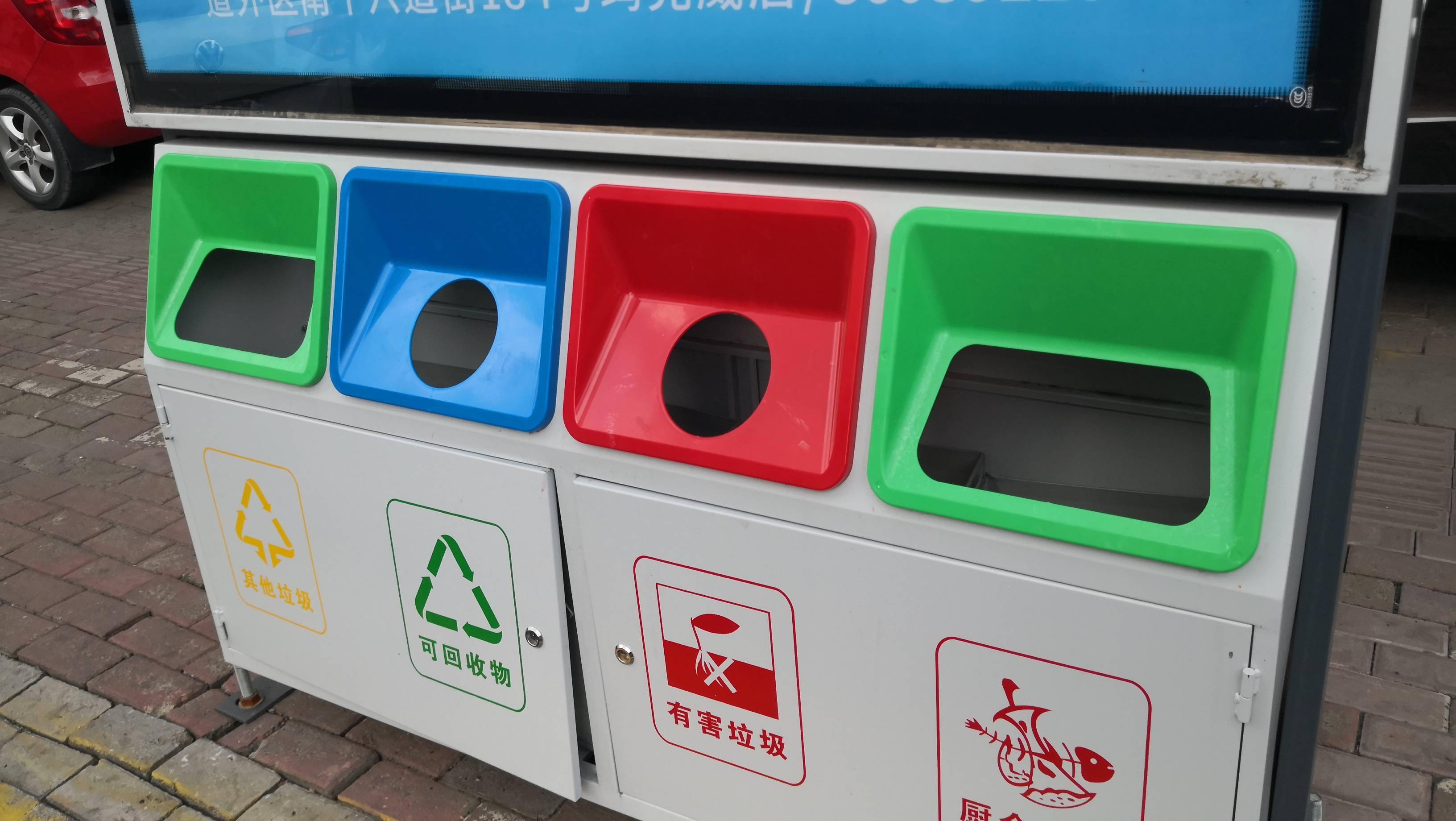 其顶部是一块太阳能板,中间一个广告牌,下面是"有害垃圾","可回收垃圾