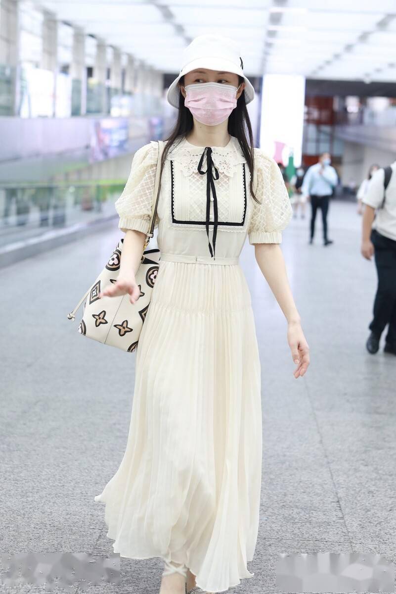 街拍:舒畅身穿白色娃娃领百褶裙清新亮丽,挎卡通印花包温婉大方