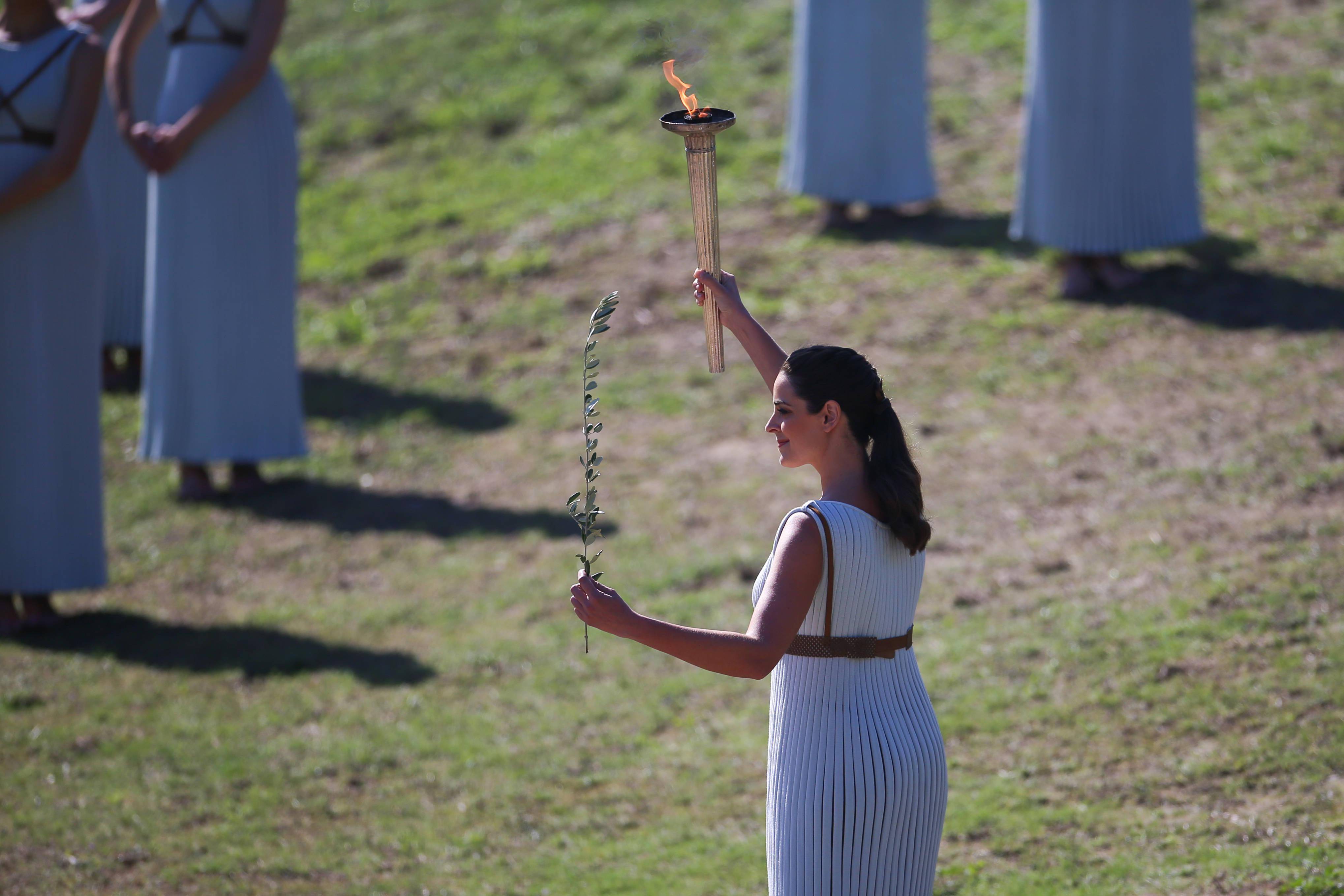 扮演最高女祭司的演员乔治乌在火种采集仪式上手持火炬与橄榄枝