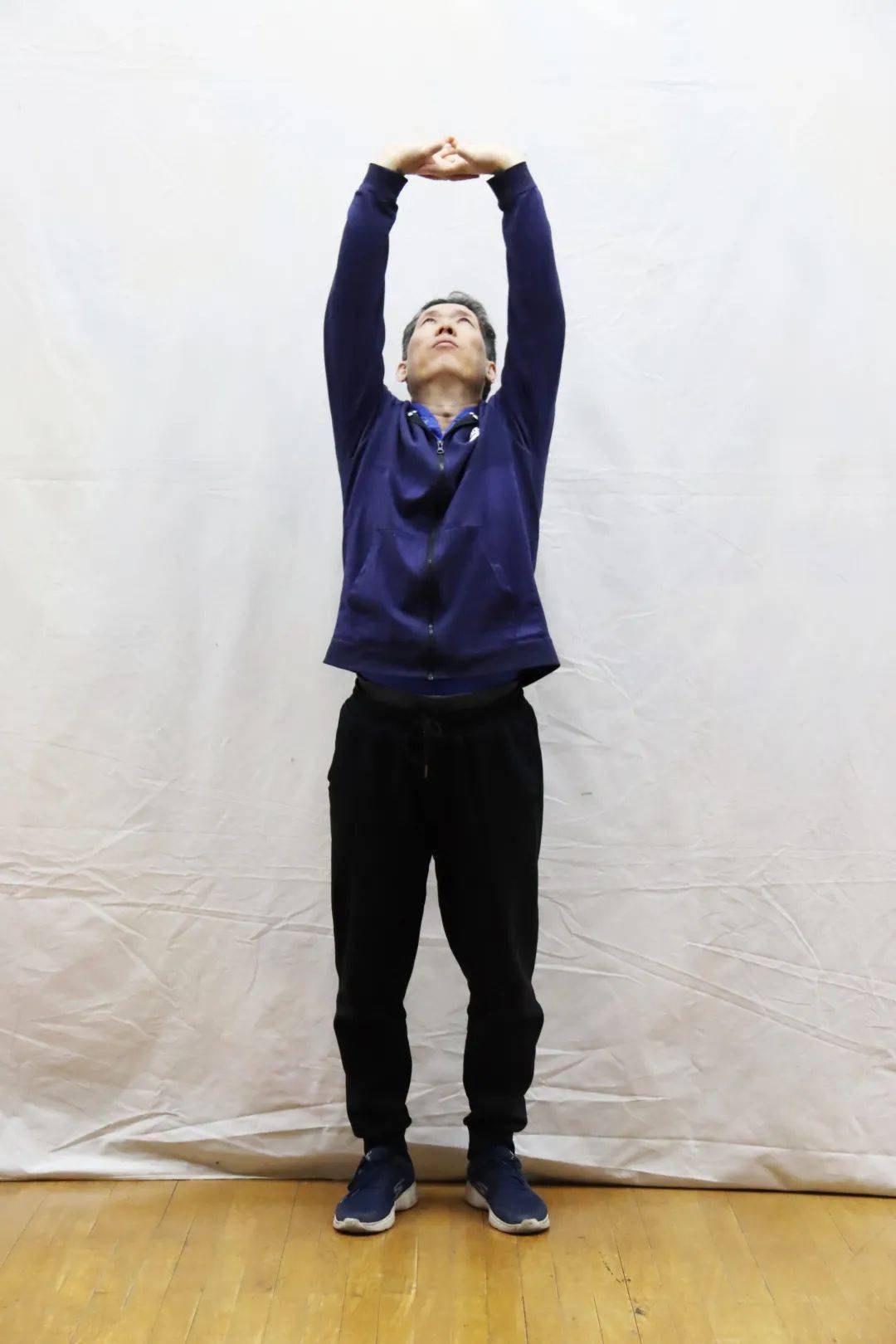 双手沿身体正中向上托至胸口高度,右转身约45度,掌心外翻,双手向右