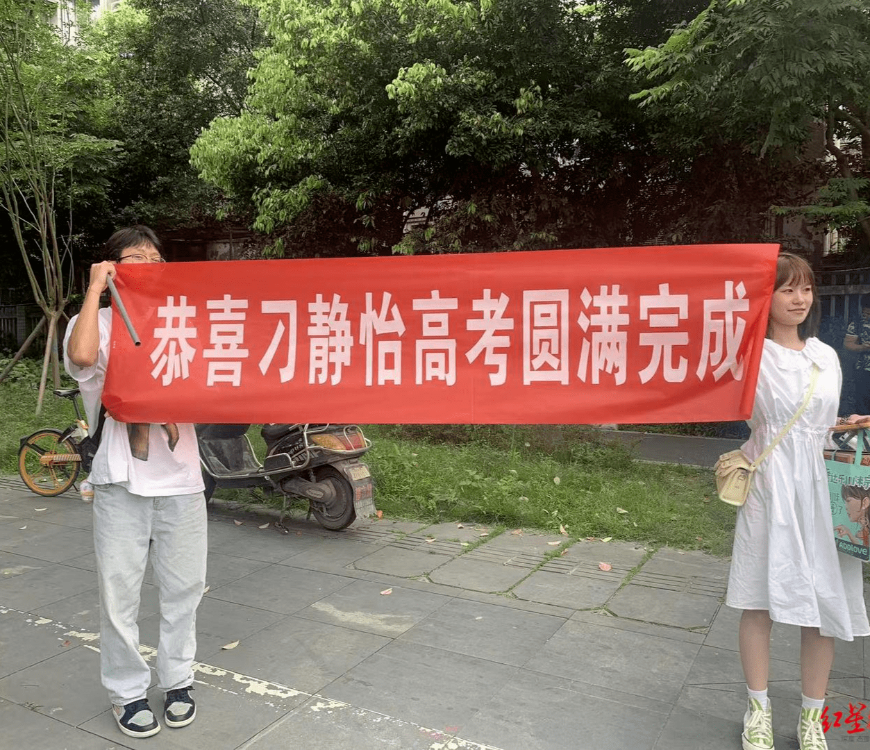 中考点外,除了家长,还有几位学生,他们拉起"恭喜高考圆满完成"的横幅