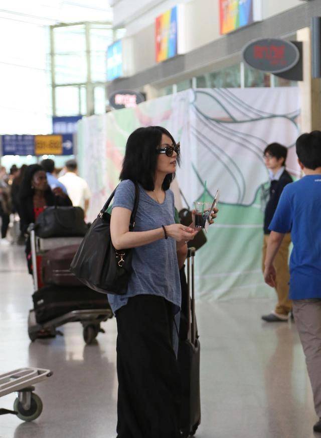 王菲机场穿搭真低调,灰色t恤配灯笼裤好随性,50岁发量太惊人_发型