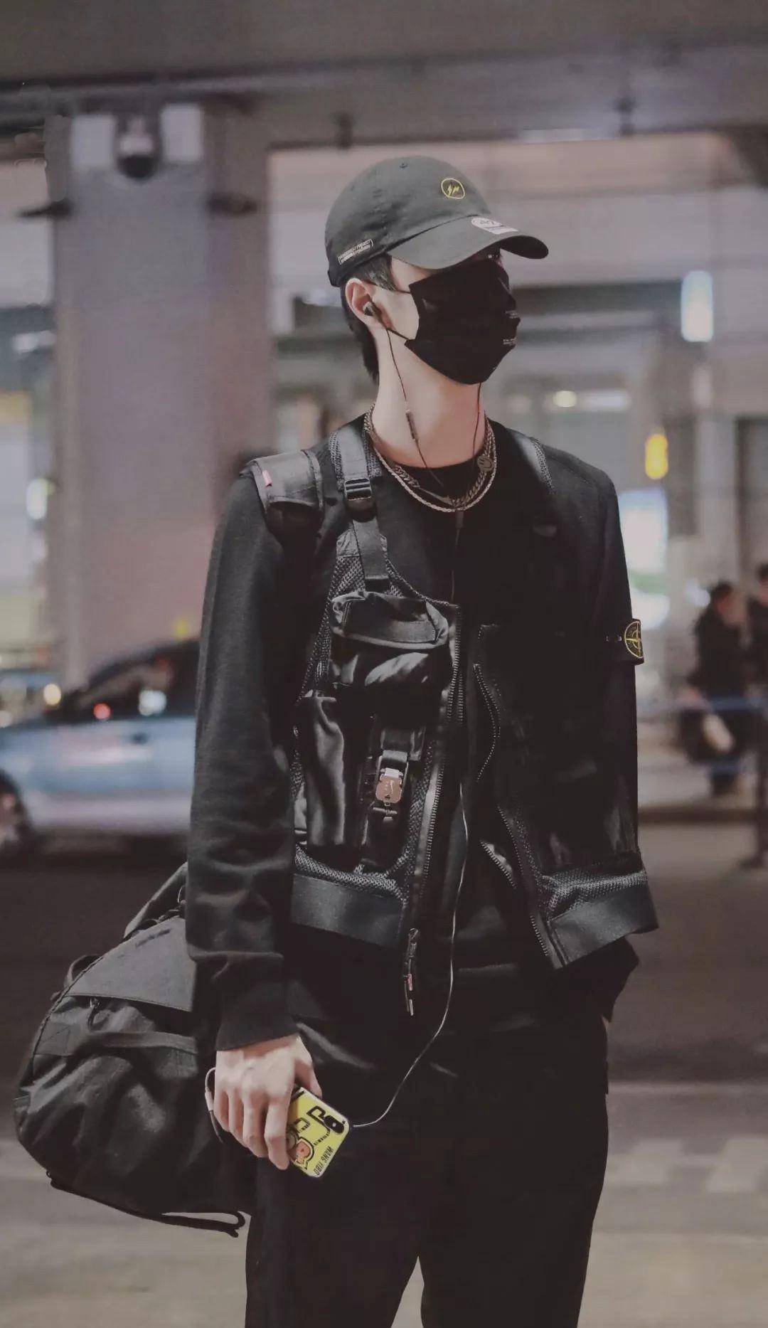 是王一博在机场的图片,他身穿黑色的卫衣,并且外面还有一件工装马甲