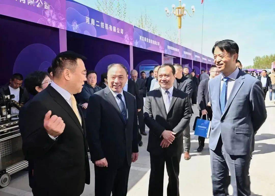 天门纺机总经理焦伦进向莅临公司展位的晋州市长王林(右2),中国服装