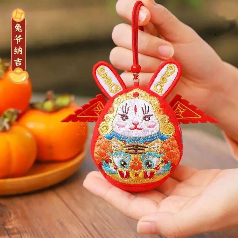采用老北京传统兔爷儿形象,披红袍,插令旗,笑眯眯地抱着吉祥物,生动传